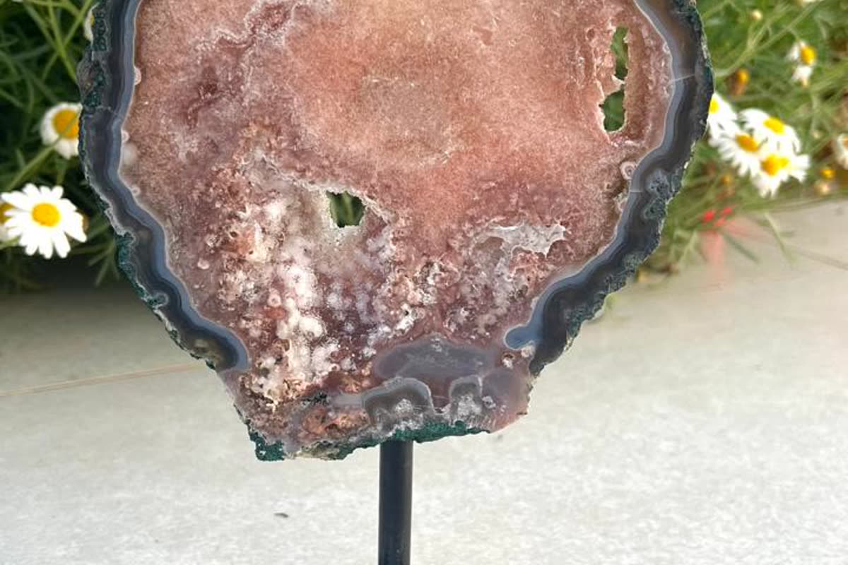 Polished agate slice on a stand, photographed in daylight the way a good website shows crystals you buy