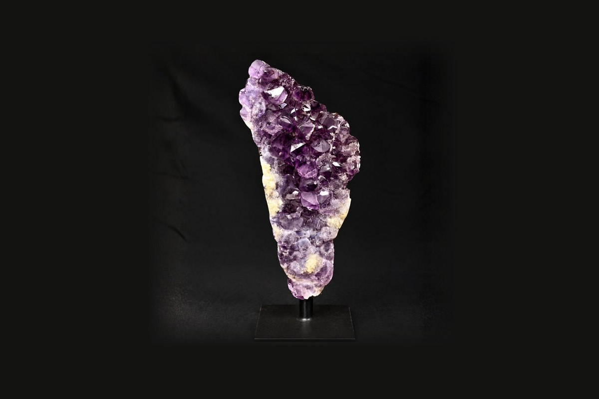 An amethyst cluster mounted on a black metal stand