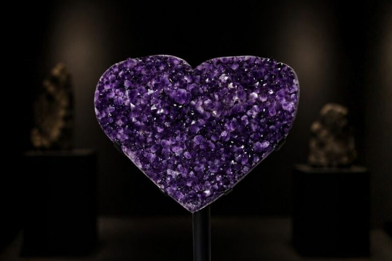 An amethyst heart on a black stand in a dark showroom