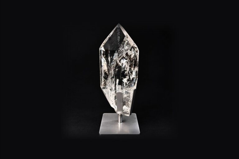 A clear quartz point mounted on a brushed steel stand
