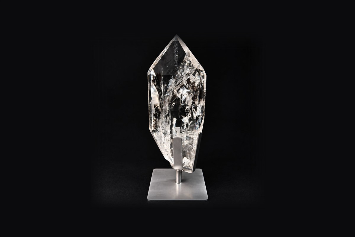 A clear quartz point mounted on a brushed steel stand