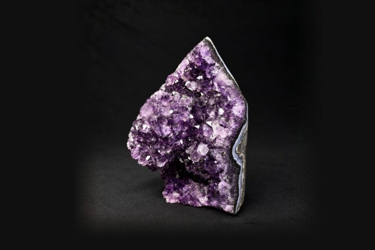 A deep purple amethyst cluster standing on a black background