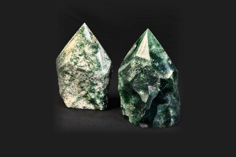 Two polished green crystal points standing on a black background