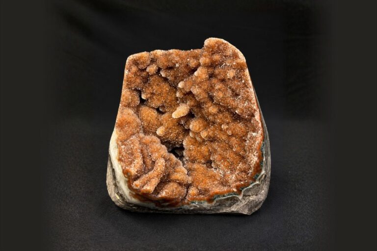 An orange druzy crystal specimen on a black background