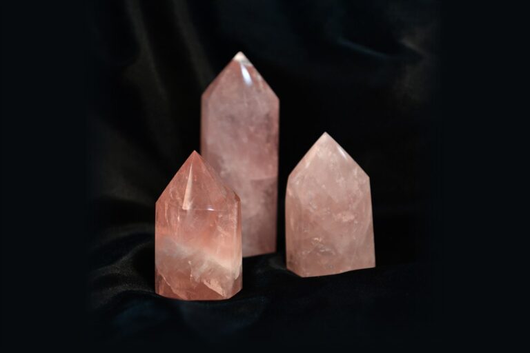 Three polished rose quartz points on a black background