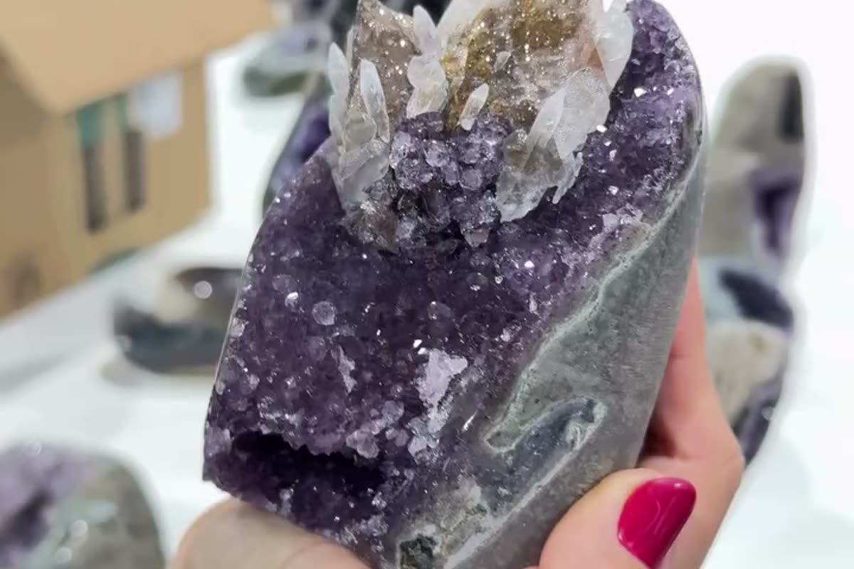 A Brazilian amethyst geode half with deep purple crystal lining, photographed against the grey exterior of the nodule