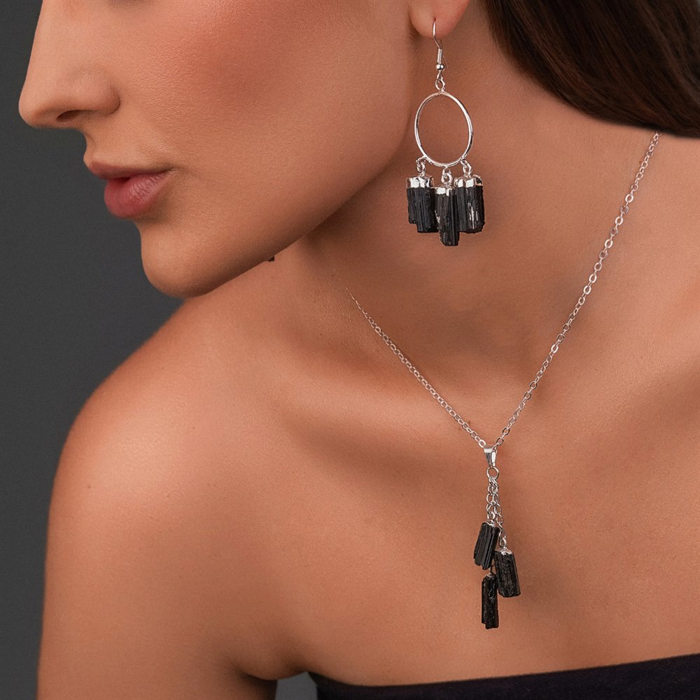 A model wearing black tourmaline earrings and a matching pendant