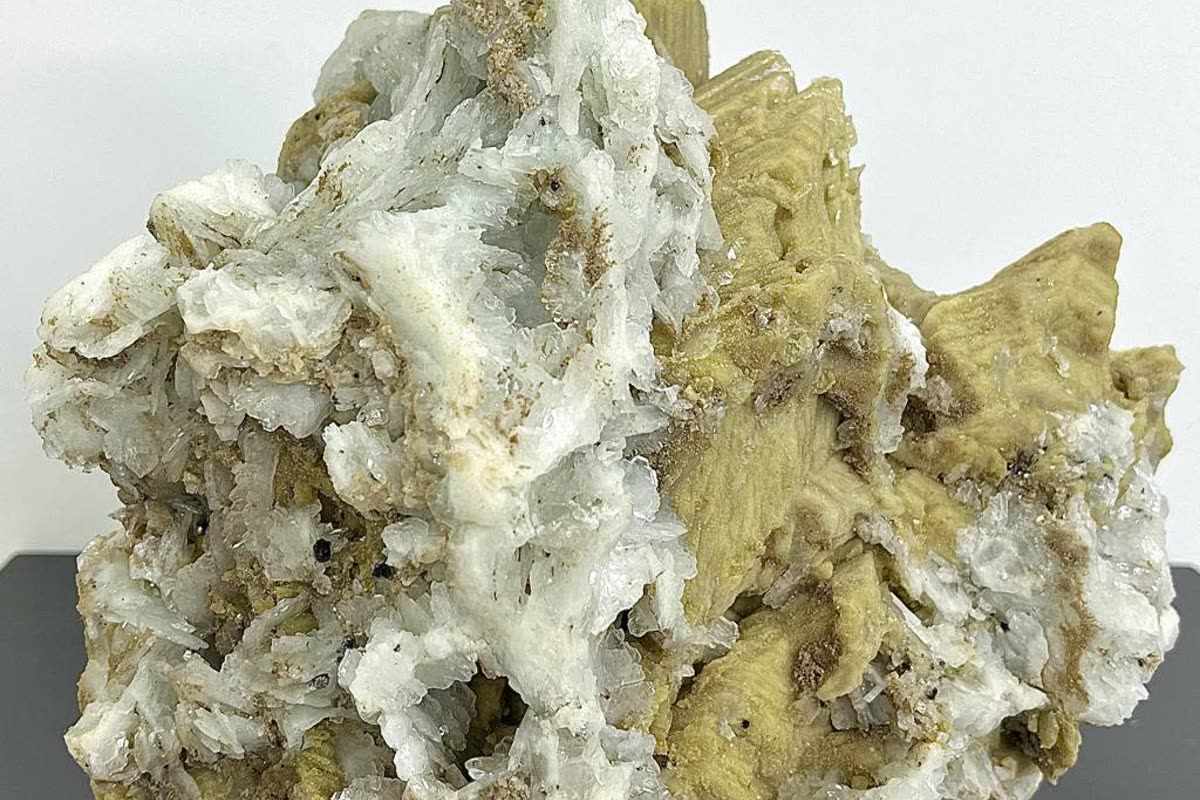 White and pale yellow zeolite specimen on a dark surface, a premium-tier piece retailers buy wholesale alongside common crystals