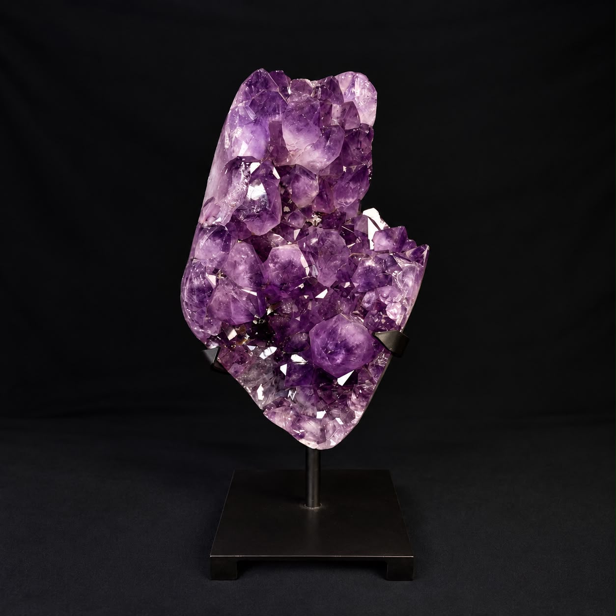 Purple amethyst crystal cluster on a black display stand