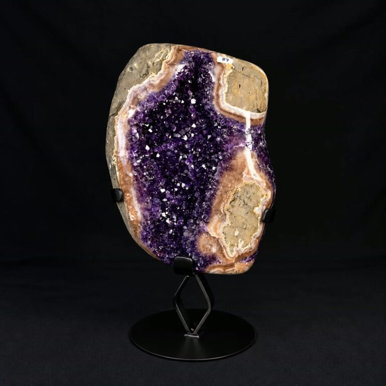 Polished amethyst geode with orange and cream agate bands, mounted on a black metal stand